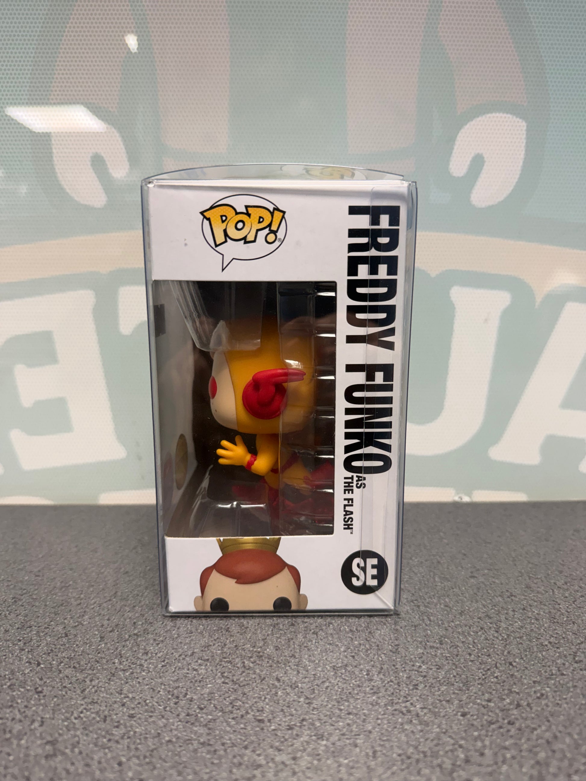Window side of Freddy Funko as The Flash Chase Pop! SE showing the yellow costume and red earpieces.